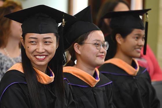 Photo of three 2024欧洲杯官方投注 international students at graduation in caps and gowns